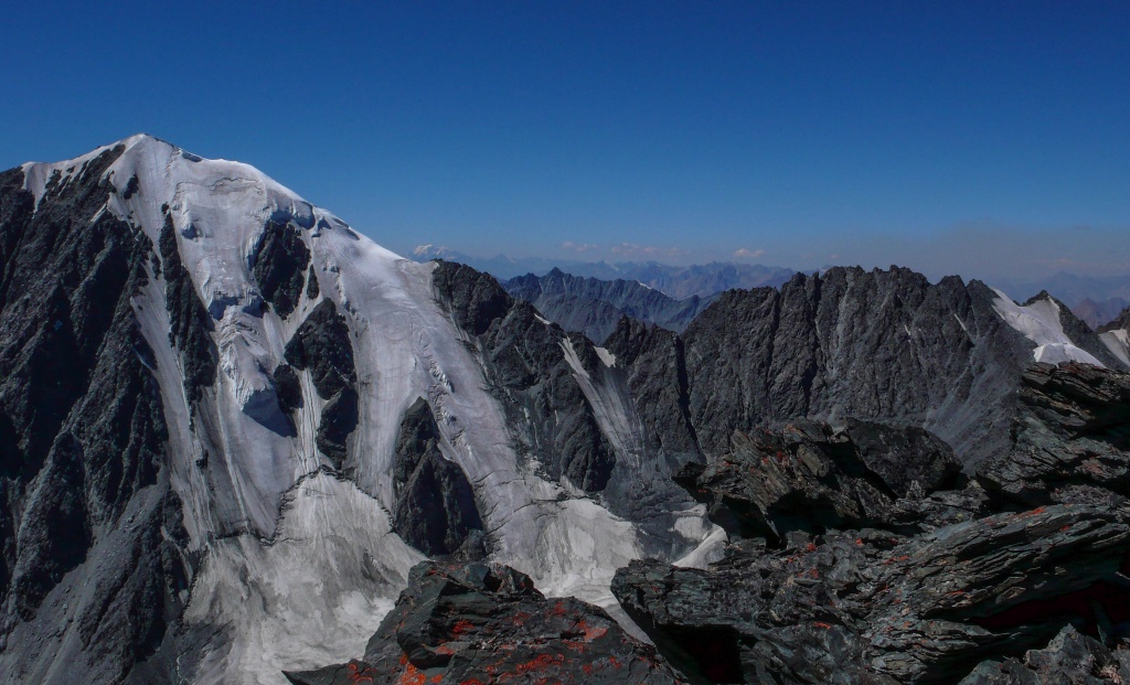 Za szczytem Metalurg (3933m) widoczny w oddali masyw Biełuchy (Белуха) (4506m) najwyższego szczytu Ałtaju.